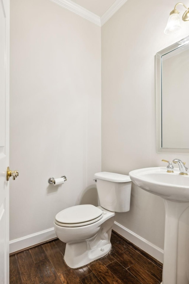 half bath with ornamental molding, baseboards, and wood finished floors