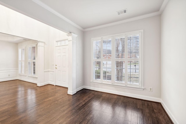 spare room with decorative columns, visible vents, dark wood finished floors, wainscoting, and ornamental molding