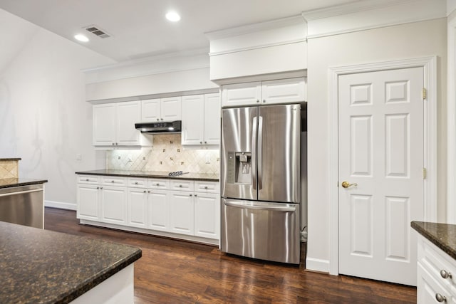 kitchen featuring white cabinets, under cabinet range hood, stainless steel appliances, and dark stone countertops