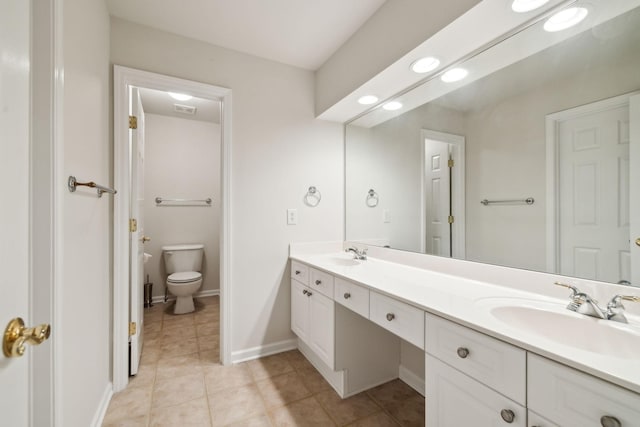 full bathroom with double vanity, a sink, toilet, and tile patterned floors