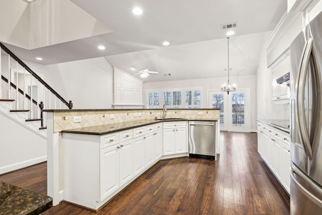 kitchen featuring stainless steel appliances, a sink, white cabinetry, dark wood finished floors, and decorative light fixtures