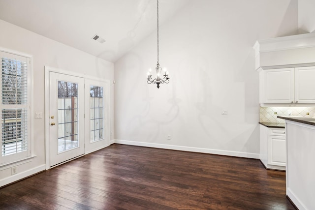 unfurnished dining area with dark wood-style floors, plenty of natural light, a chandelier, and vaulted ceiling