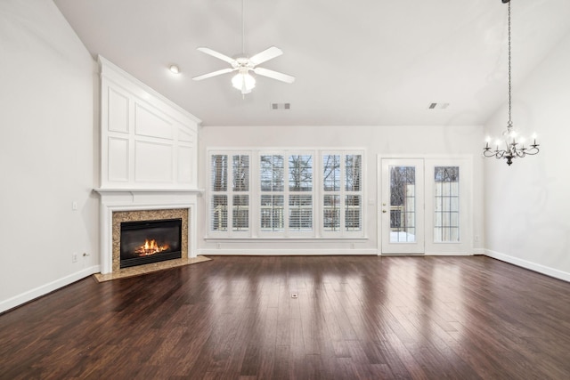 unfurnished living room with baseboards, visible vents, dark wood-type flooring, vaulted ceiling, and ceiling fan with notable chandelier