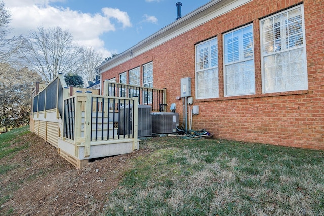 exterior space featuring a yard, brick siding, and cooling unit