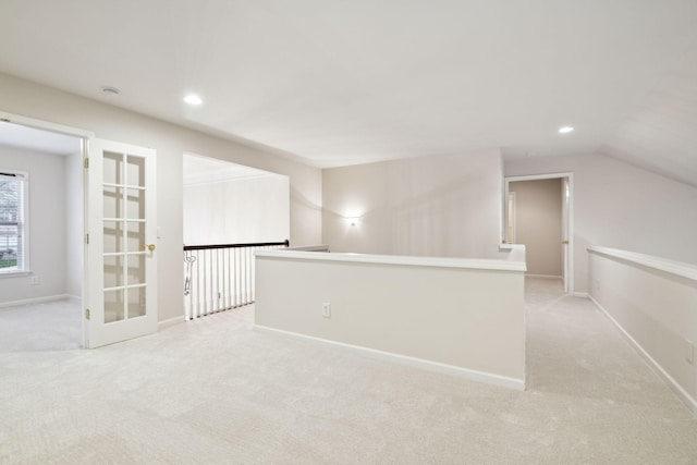 spare room featuring light carpet, lofted ceiling, baseboards, and recessed lighting