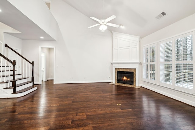 unfurnished living room with high vaulted ceiling, dark wood-style flooring, visible vents, baseboards, and stairs