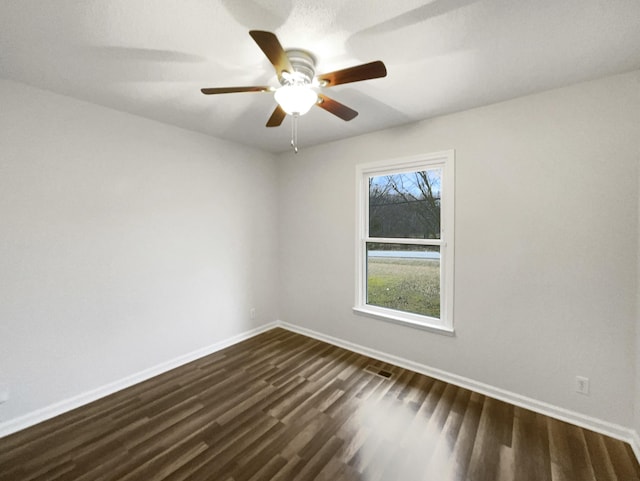 spare room with a ceiling fan, baseboards, and dark wood-type flooring