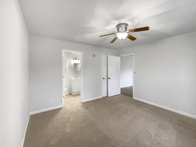 unfurnished bedroom featuring ensuite bath, carpet, baseboards, and a textured ceiling