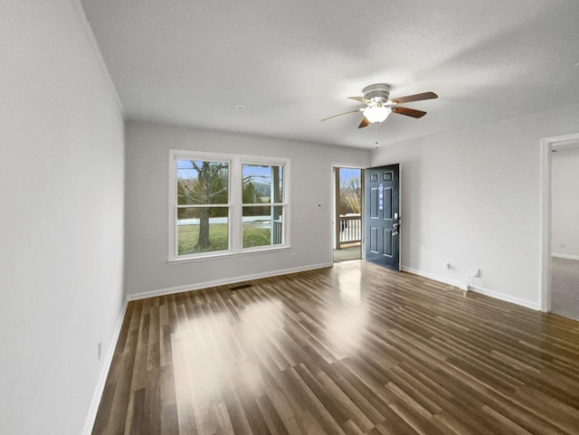 spare room with dark wood-style floors, ceiling fan, and baseboards