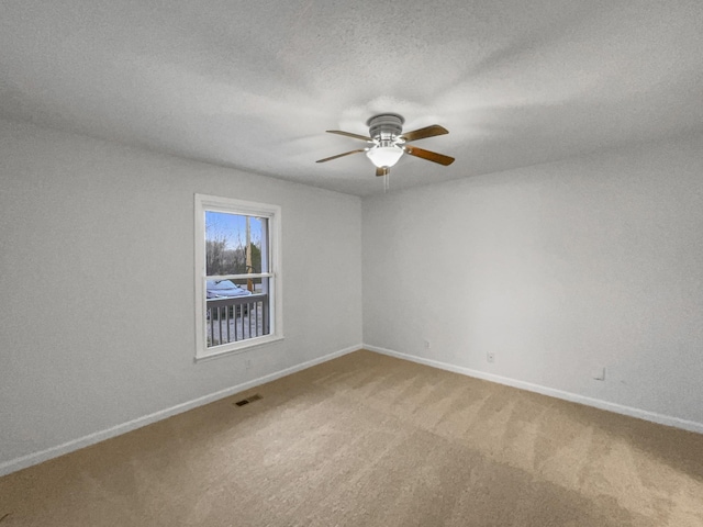 carpeted empty room featuring ceiling fan, a textured ceiling, visible vents, and baseboards