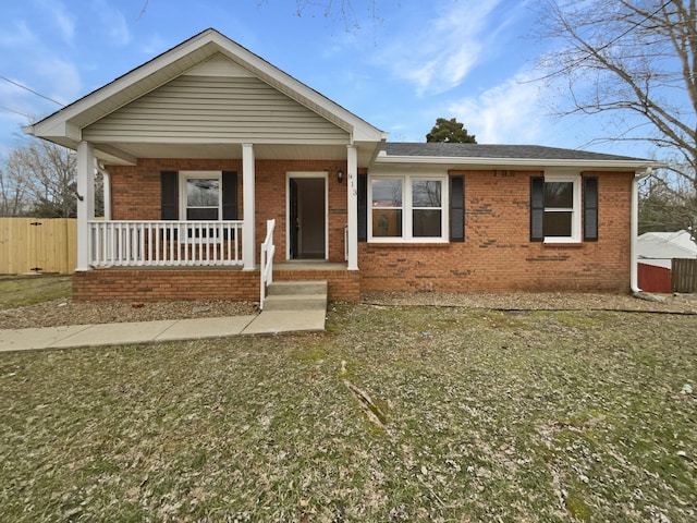 view of front of home with brick siding, a porch, and fence