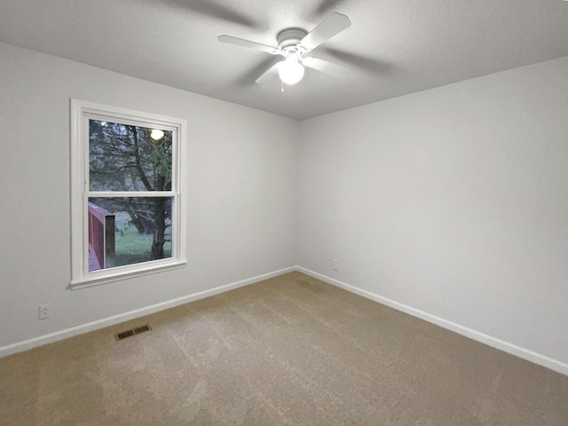 empty room featuring carpet floors, a ceiling fan, visible vents, and baseboards