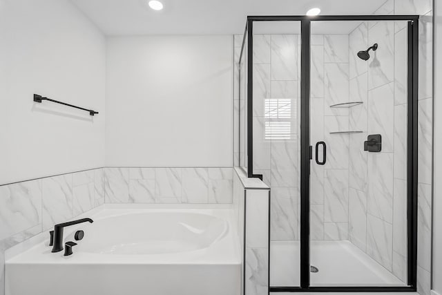 full bathroom with a stall shower, a garden tub, and recessed lighting