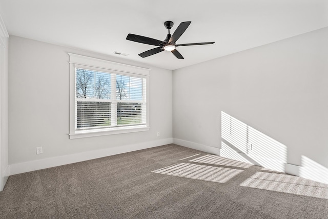 carpeted spare room with baseboards, visible vents, and a ceiling fan