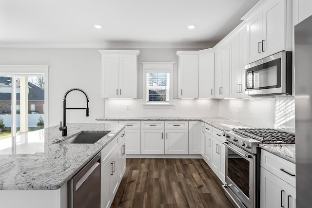 kitchen featuring stainless steel appliances, light stone counters, a sink, and white cabinets