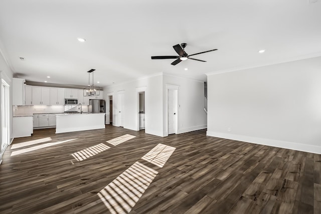 unfurnished living room with dark wood-style floors, crown molding, a sink, and recessed lighting