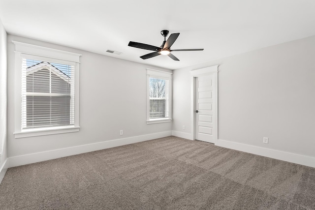 carpeted spare room featuring ceiling fan, visible vents, and baseboards