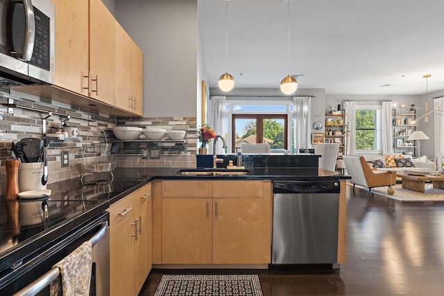 kitchen featuring light brown cabinets, open floor plan, hanging light fixtures, appliances with stainless steel finishes, and dark countertops