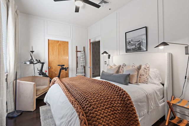 bedroom featuring visible vents, dark wood finished floors, a decorative wall, and ceiling fan