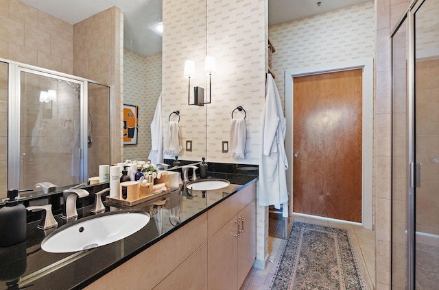 full bath featuring double vanity, a stall shower, a sink, and tile patterned floors