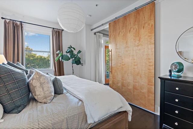 bedroom with a barn door and wood finished floors