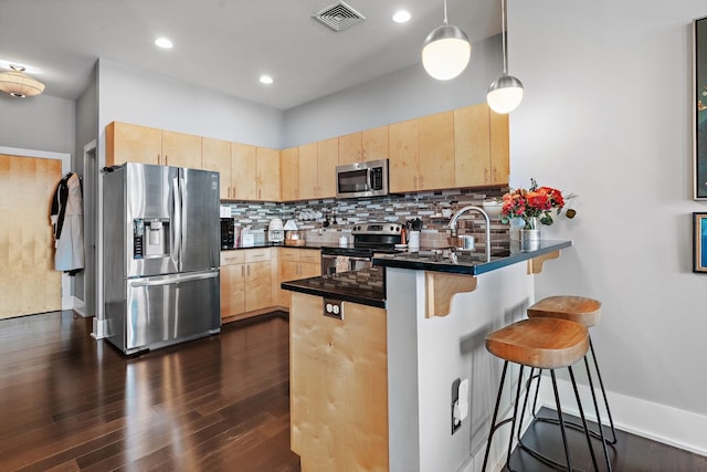 kitchen with dark countertops, stainless steel appliances, decorative light fixtures, and light brown cabinetry