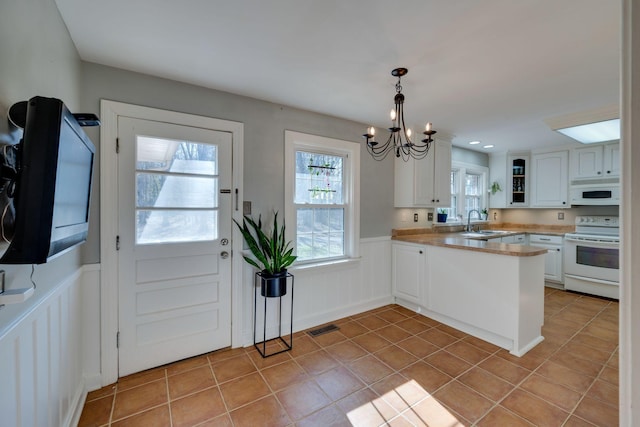 kitchen featuring a wainscoted wall, visible vents, white cabinetry, a sink, and white appliances