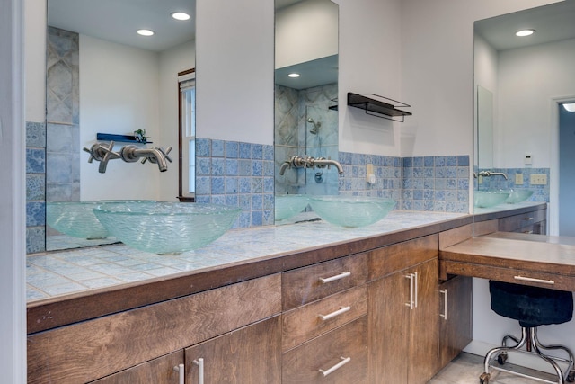 bathroom with tiled shower, a sink, and double vanity