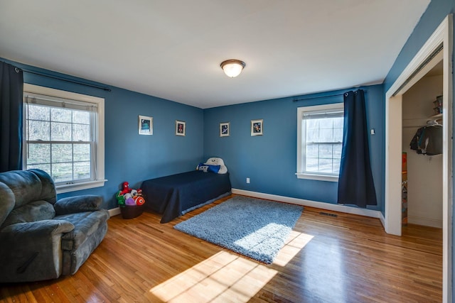 bedroom featuring baseboards, a closet, visible vents, and wood finished floors