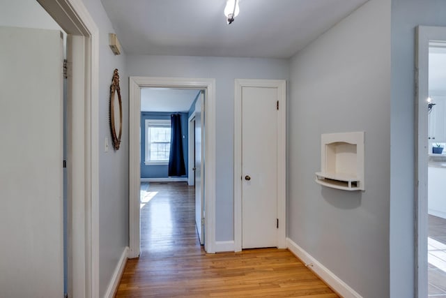 corridor with light wood finished floors and baseboards