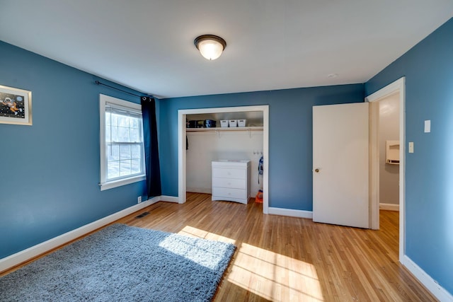 unfurnished bedroom with a closet, wood finished floors, and baseboards