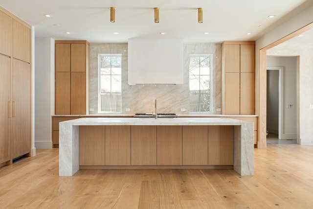 kitchen with light countertops, modern cabinets, a sink, and a kitchen island with sink