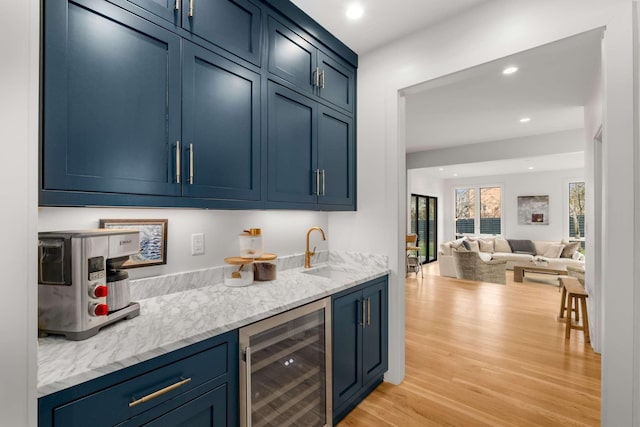 bar with light wood finished floors, beverage cooler, wet bar, a sink, and recessed lighting