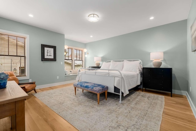 bedroom featuring light wood-type flooring, multiple windows, and baseboards