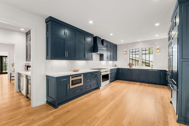 kitchen with stainless steel appliances, recessed lighting, backsplash, light wood-type flooring, and wall chimney exhaust hood