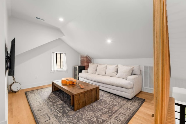 living room with lofted ceiling, wood finished floors, visible vents, and baseboards