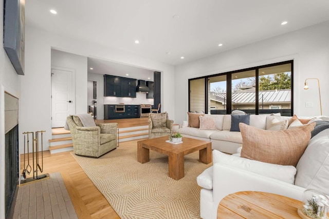 living room with a fireplace, light wood-style flooring, and recessed lighting