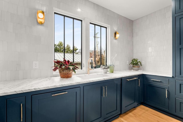 bar with tasteful backsplash, a sink, and light wood-style flooring