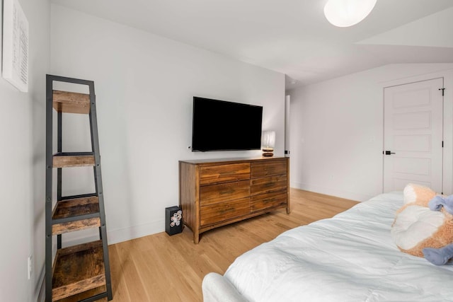 bedroom featuring baseboards, vaulted ceiling, and light wood finished floors