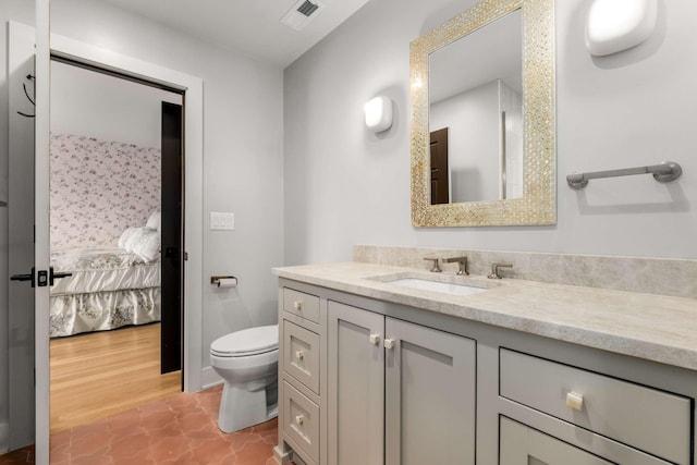 ensuite bathroom featuring visible vents, toilet, vanity, and ensuite bath