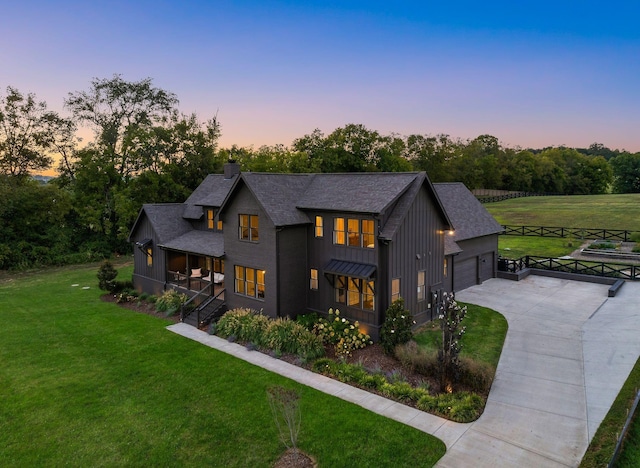 modern farmhouse featuring a shingled roof, a yard, driveway, board and batten siding, and a chimney