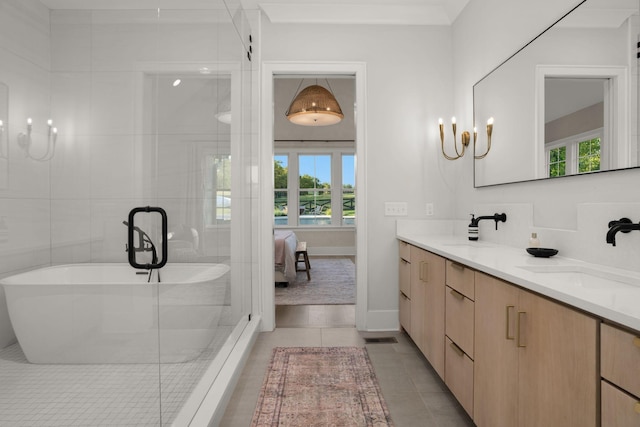 ensuite bathroom with double vanity, ensuite bath, tile patterned floors, a freestanding bath, and a sink