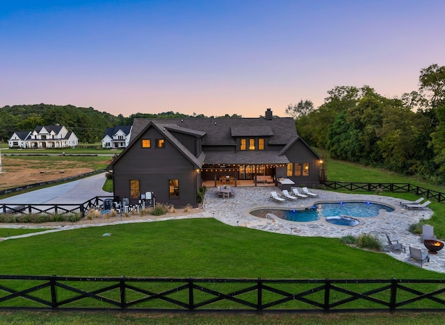 back of property at dusk with a lawn, a patio area, fence, and a fenced in pool