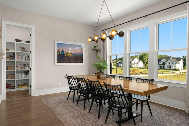 dining room with a chandelier, dark wood-style flooring, a residential view, and baseboards