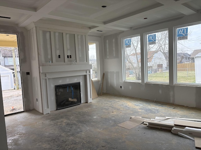 unfurnished living room with plenty of natural light, coffered ceiling, beamed ceiling, and a glass covered fireplace