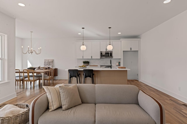 living room with a chandelier, recessed lighting, light wood-style flooring, and baseboards