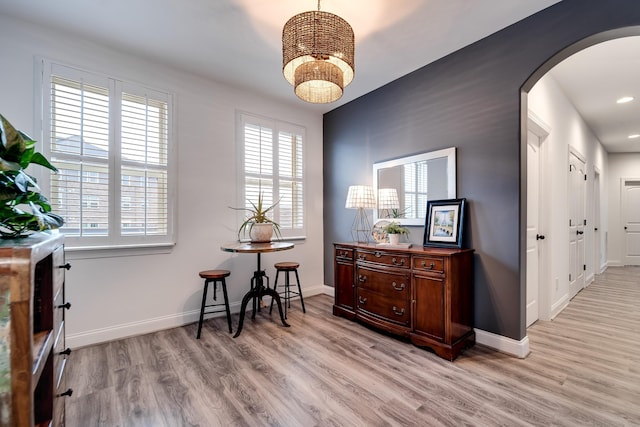 interior space featuring arched walkways, light wood-type flooring, and plenty of natural light