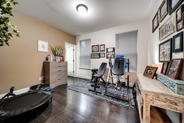 workout area with dark wood-style floors and baseboards