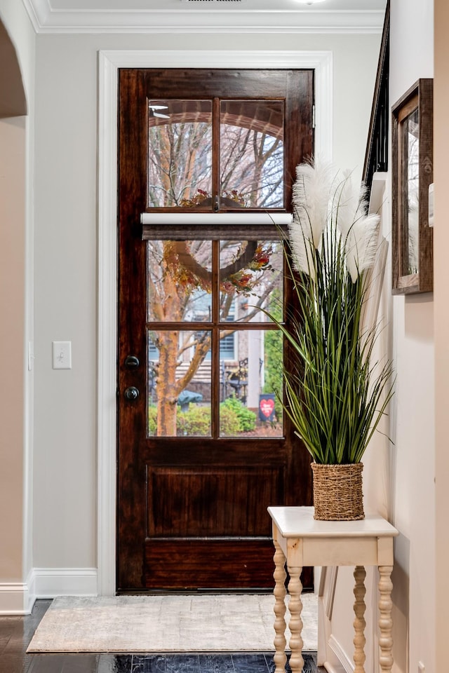 entrance foyer with baseboards, arched walkways, and crown molding