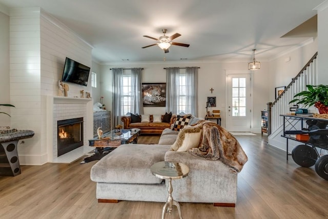 living room with light wood finished floors, stairway, a fireplace, and crown molding